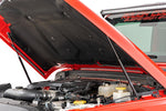 a red jeep sits with an open hood, displaying installed hood struts