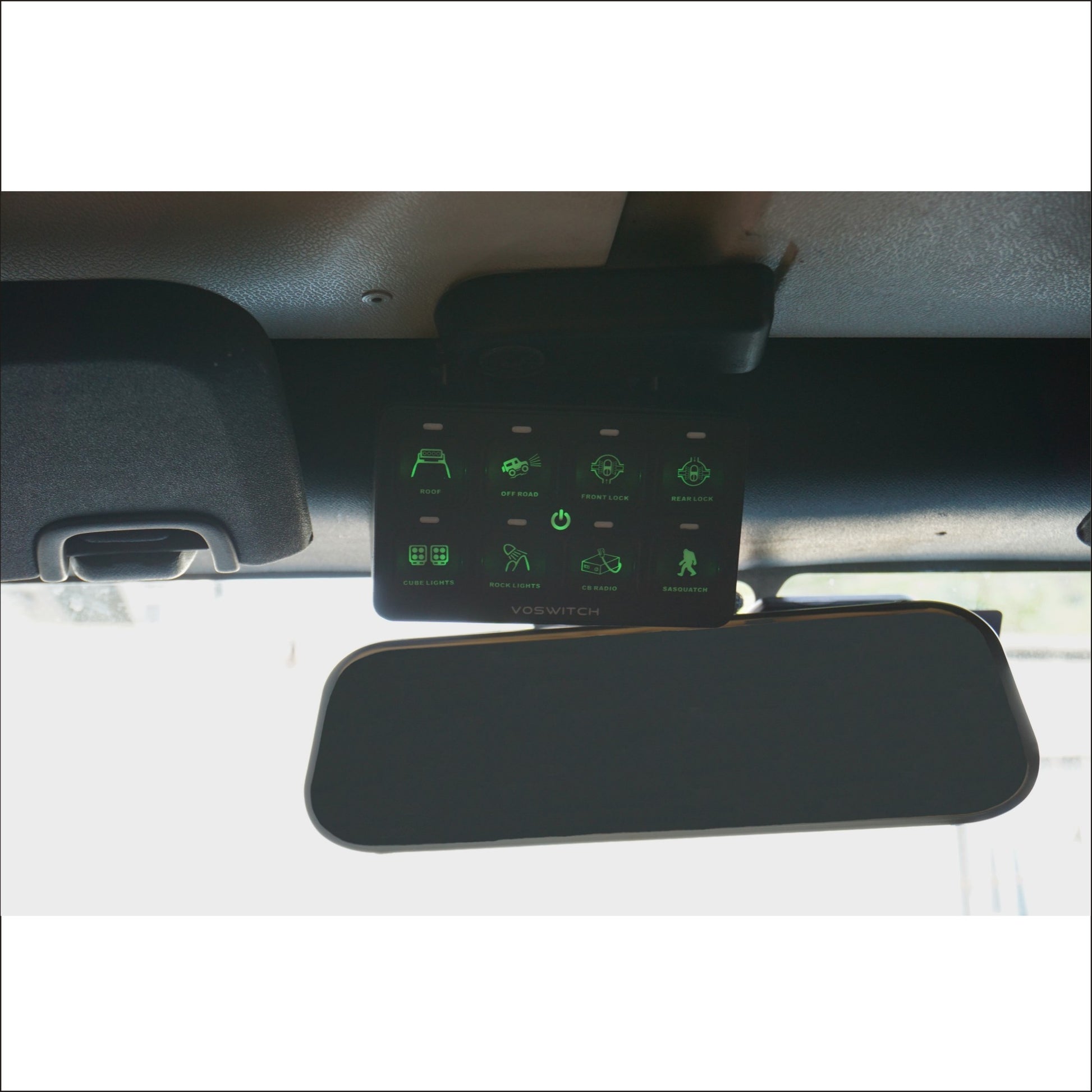 a control system with lit green buttons installed by a rearview mirror