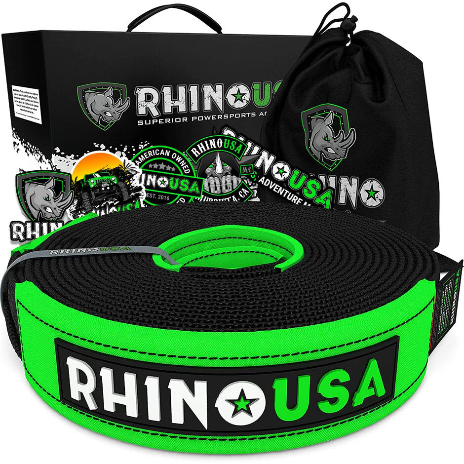 a green and black tow strap is coiled up in front of its packaging and drawstring carrying bag